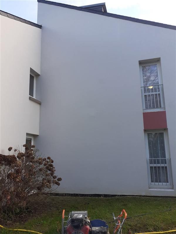 Façade enduite blanche après nettoyage et traitement anti-algues : le mur est uniforme