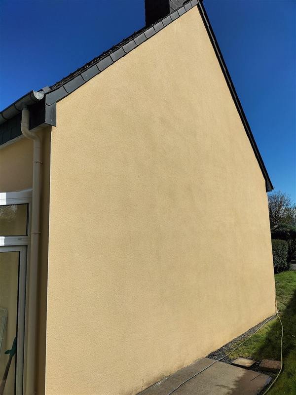 Le pignon après démoussage, crépi jaune clair uniforme sous un ciel bleu