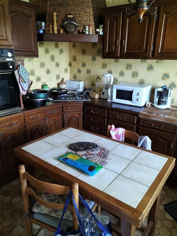 Cuisine encombrée avec table, chaises et électroménager, avant le vide-maison