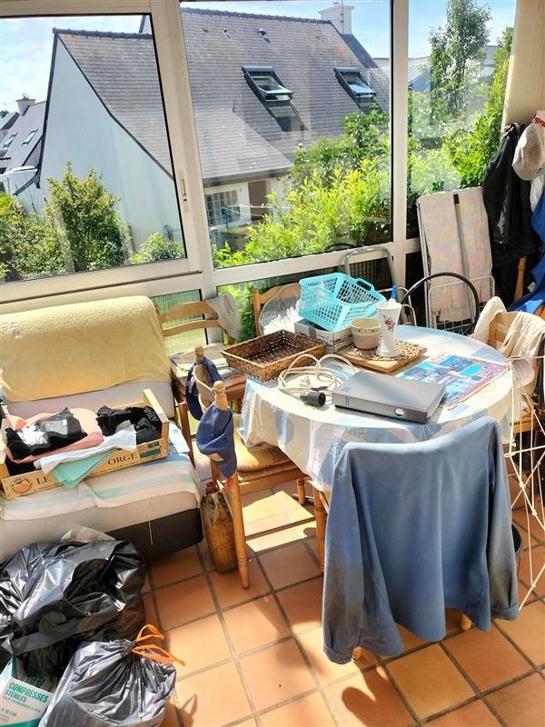 Véranda remplie de meubles, de sacs et de cartons, avant le vide-maison